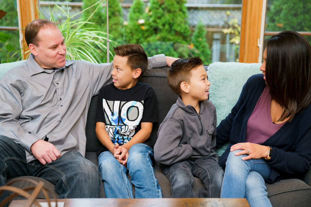 A family sits together on a couch in conversation.