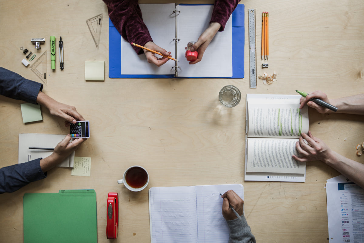 Overhead view of people studying around a table with books and notes.