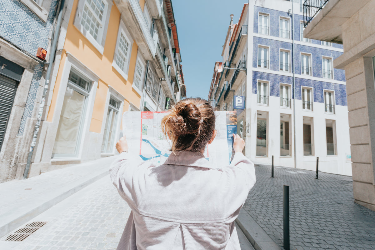 A person holds an unfolded map while standing on a city street.