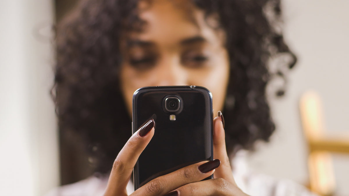 A woman holds a smartphone in front of her face.