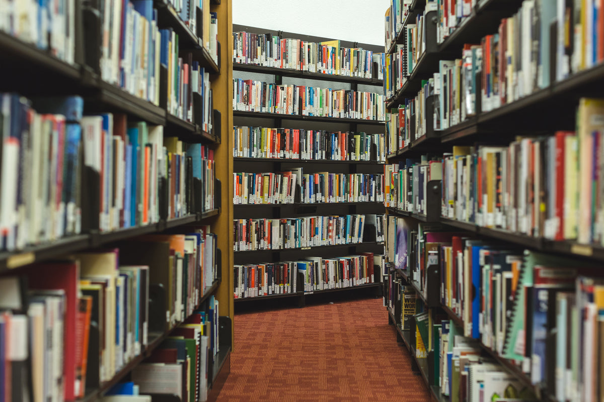 An aisle between shelves filled with library books.