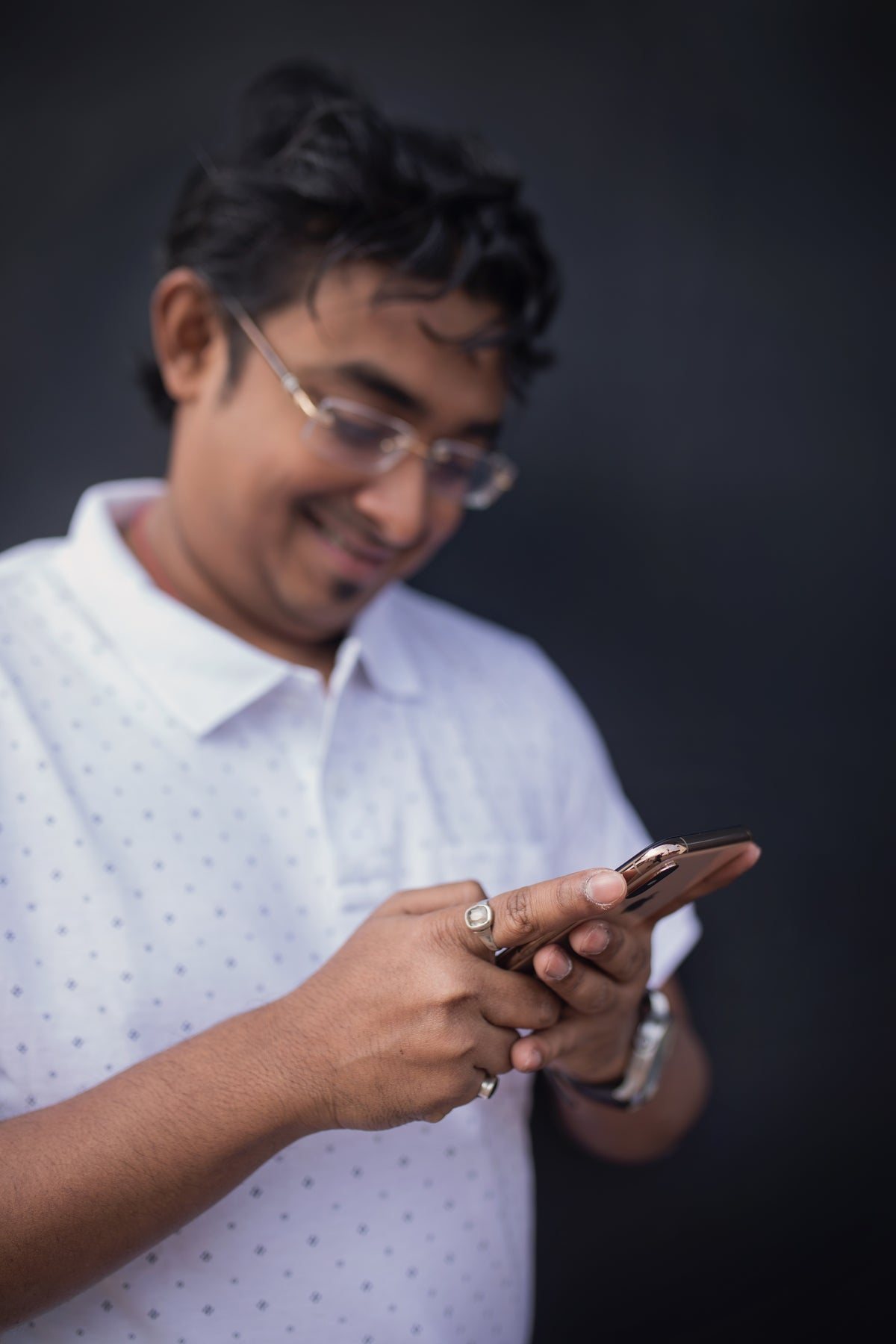 A man wearing glasses looks at his smartphone.