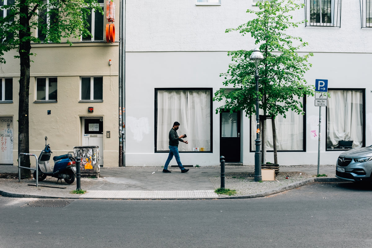 A person looks at a smartphone while walking along a city street.