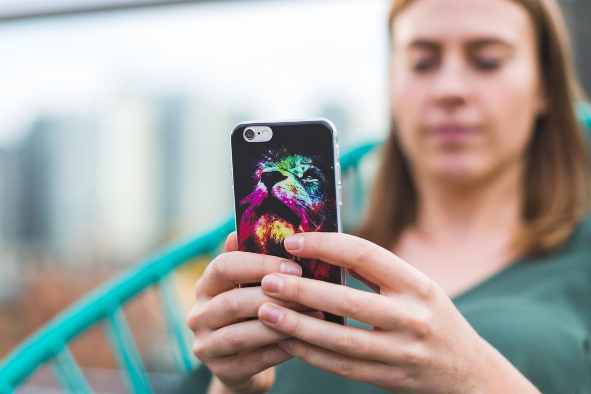 A woman holds a smartphone outdoors.