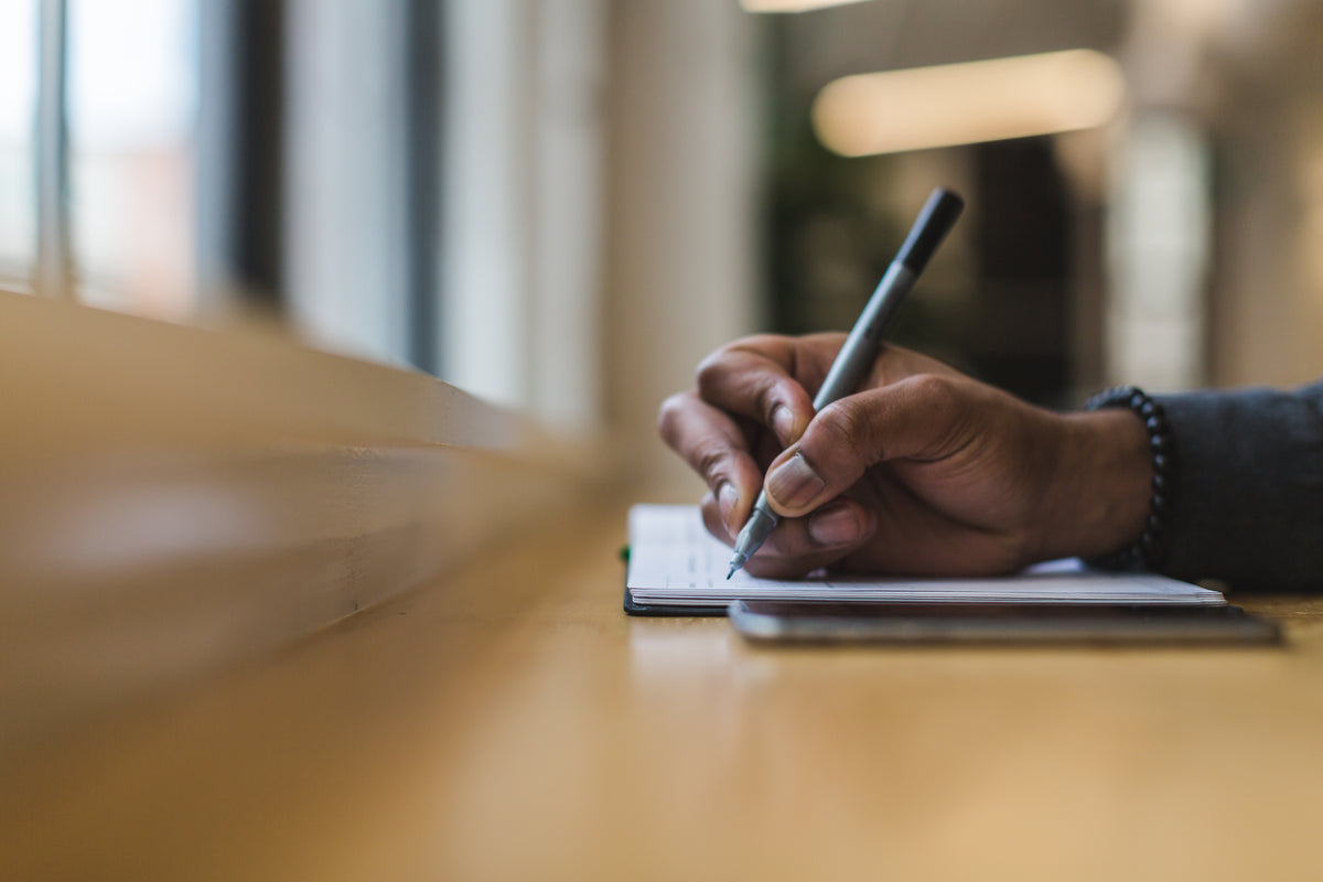 A hand writes careful notes in an open journal.