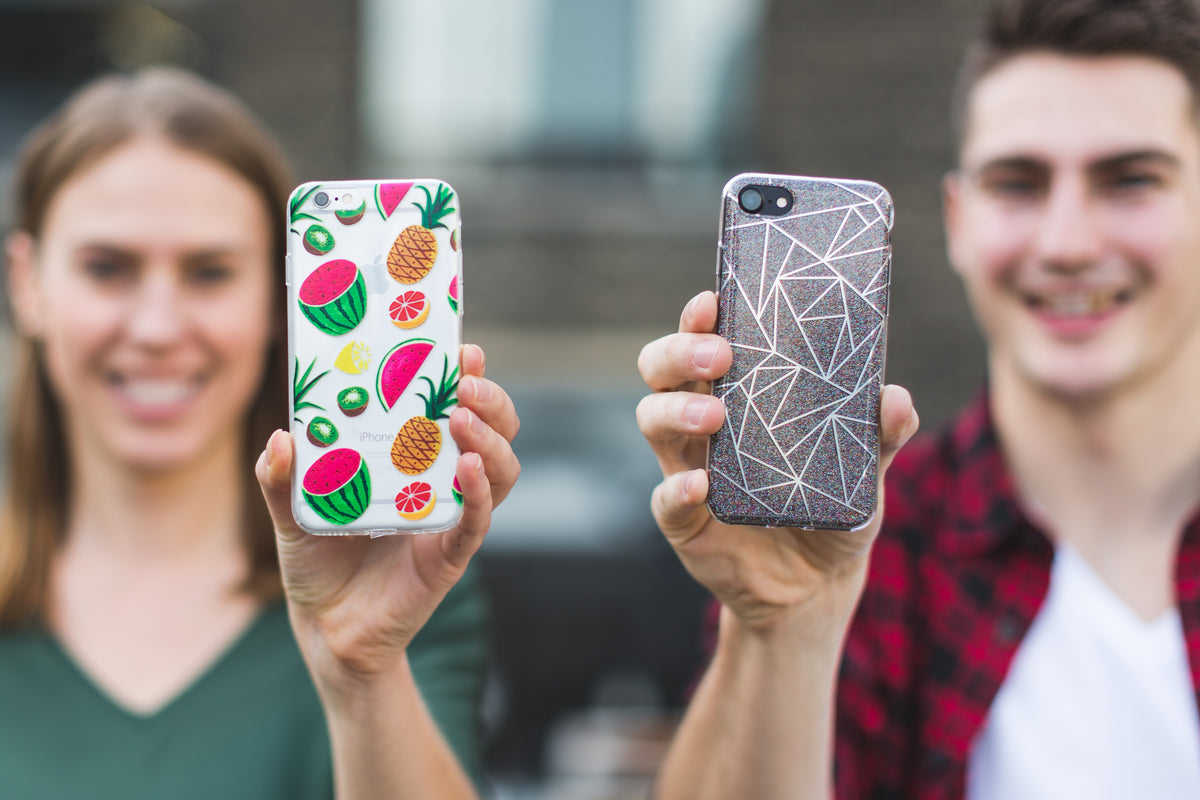 Two people hold up smartphones with colorful cases.