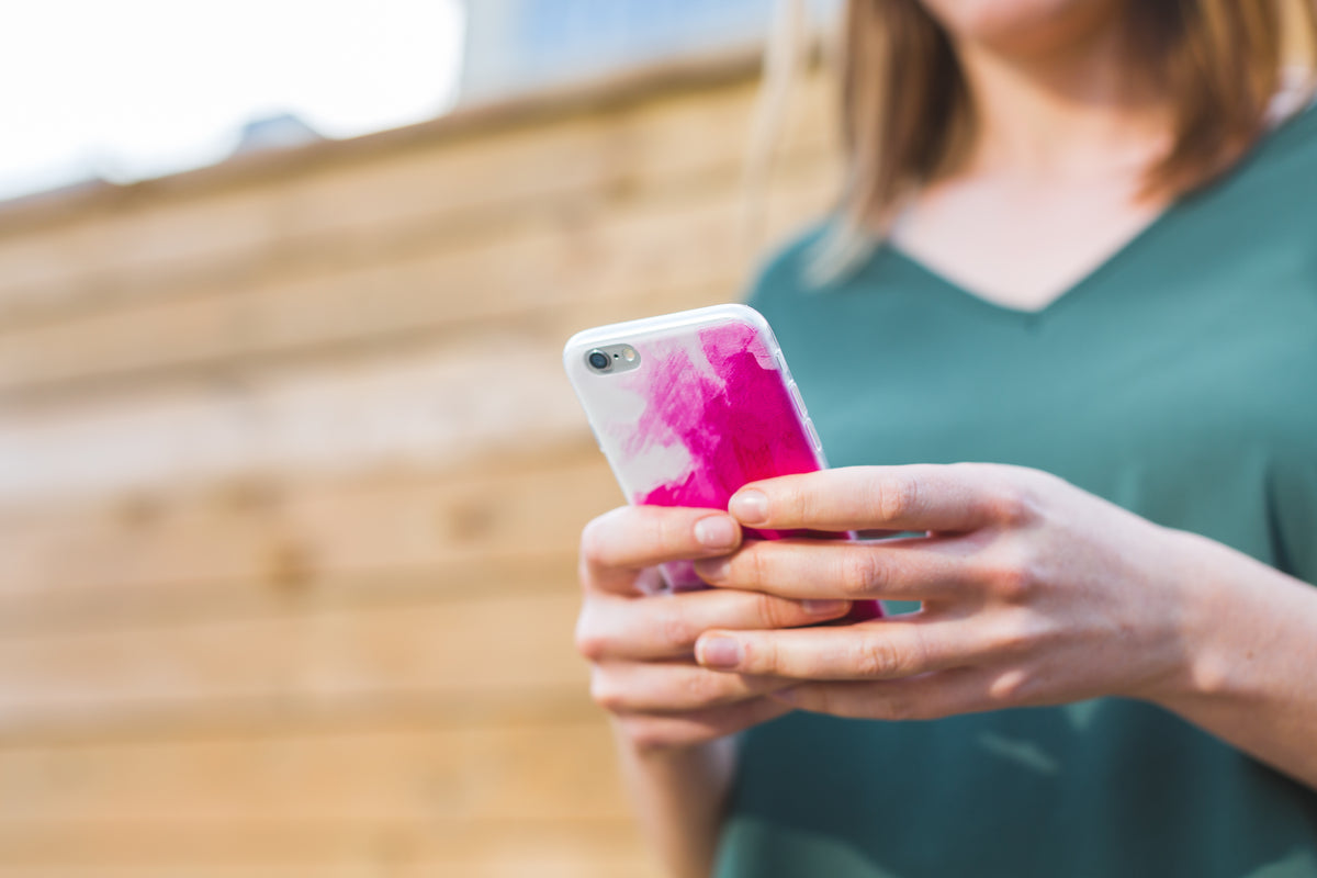 Close-up of a person using a phone in a pink case.
